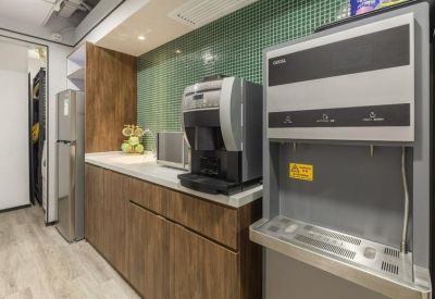 Kitchenette area with coffee machine, water dispenser, and wooden cabinetry.