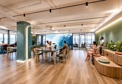 Open-plan coworking space with a large digital wall and tiered seating.