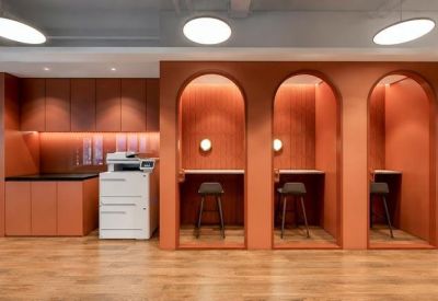 Terracotta-colored individual workspace booths with high stools and integrated lighting.