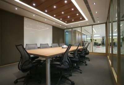 Professional boardroom with a wood-top table, mesh executive chairs, and glass partitions.