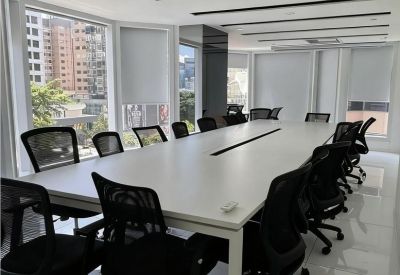 Large professional boardroom with a white conference table and black mesh chairs.