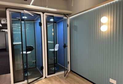 Private soundproof phone booths with glass doors and bar stool seating.