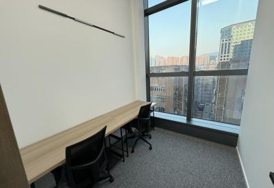 Minimalist two-person window office with a long wooden desk and black ergonomic chairs.