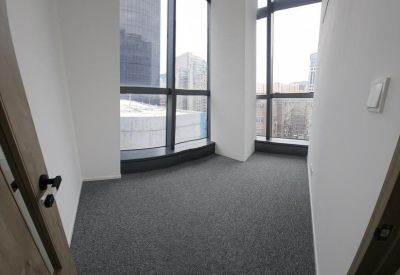Small empty office room with grey carpeting and large floor-to-ceiling windows.