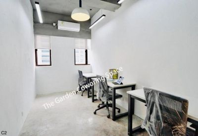 Long white private office with multiple workstations and natural light from small windows.