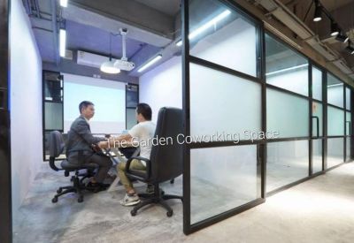 Small meeting room with frosted glass walls and a wall-mounted projector screen.