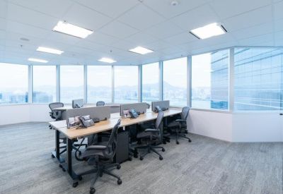 Bright, open-plan office space with multiple workstations and floor-to-ceiling windows.