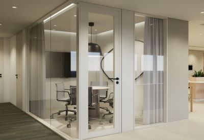 Modern glass-walled meeting room with round table and black pendant light.
