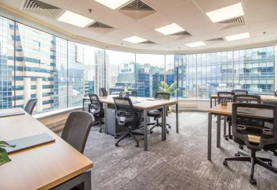 Bright workspace with multiple desks and panoramic city views through large windows.