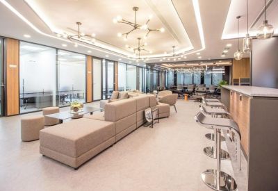 Open-plan lounge area with bar stool seating and glass-walled offices.