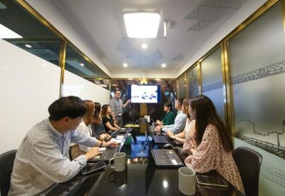 Professional meeting room with a large screen and team members collaborating around a table.