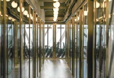 Bright office corridor with glass partitions and modern recessed lighting.