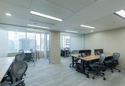 Open-plan office with multiple workstations and glass-walled private offices.