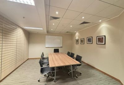 Meeting room with a light wood table, black chairs, and framed artwork on the wall.