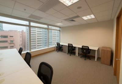 Spacious three-person office suite with white desks and floor-to-ceiling windows.