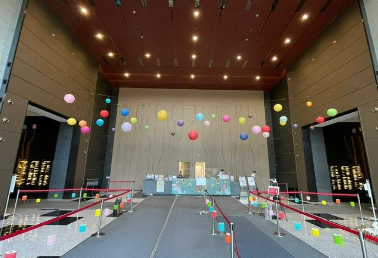 High-ceilinged building lobby decorated with colorful hanging paper lanterns.