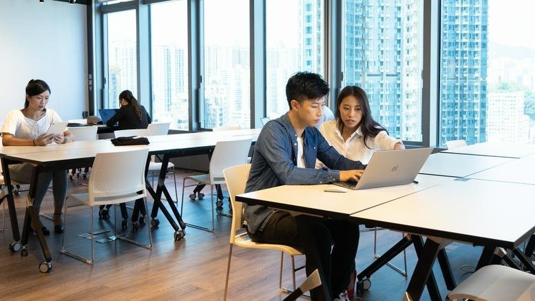 People working in a bright, open-plan workspace at Dah Sing Financial Centre with floor-to-ceiling city views.