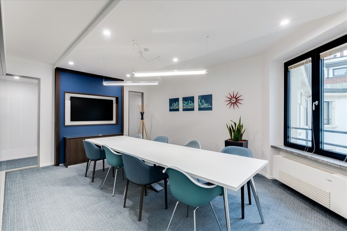 Spacious boardroom at Lee Garden Eight with teal chairs, a white table, and blue feature wall.