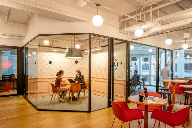 Spacious communal lounge at 33 Lockhart Road with glass-walled meeting pods and red armchairs.