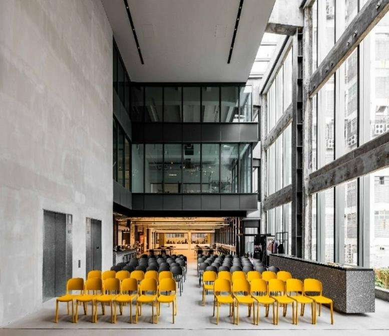 Spacious, modern atrium at The Mills with rows of vibrant yellow and grey seating and high glass walls.