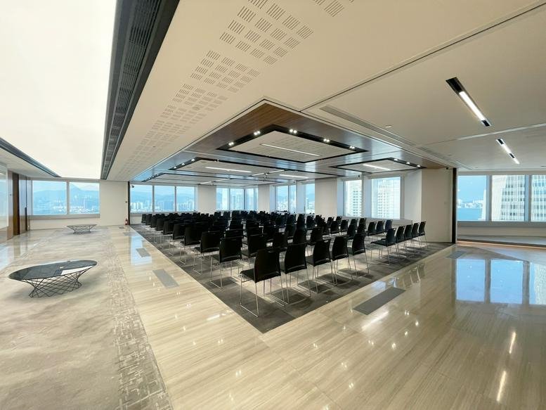 Spacious auditorium-style event space at 99 Queen’s Road Central with rows of black chairs and city views.