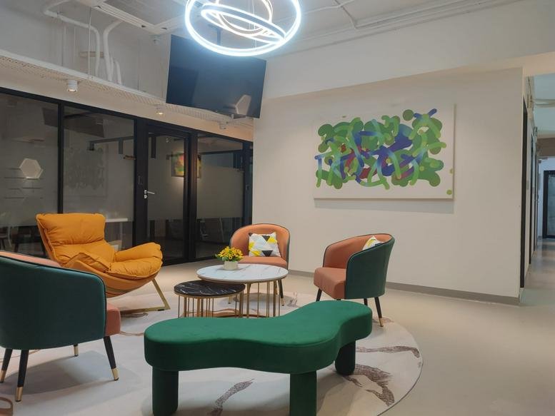 Colorful communal lounge at New Timely Factory Building with modern chairs and a vibrant abstract painting.