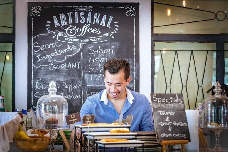 A barista at 5 Tai Mong Tsai Road, Sai Kung, Hong Kong, standing in front of an artisanal coffee menu.
