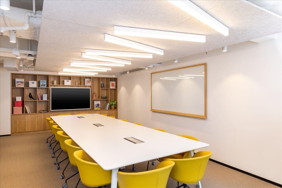 Meeting room at 8 Queen’s Road East with a large white table and vibrant yellow chairs.