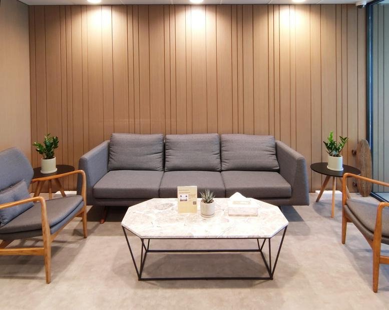 Office lounge with gray sofa, armchairs, and a marble coffee table.