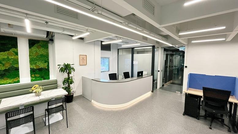 Curved reception desk in a bright office with green wall accents.