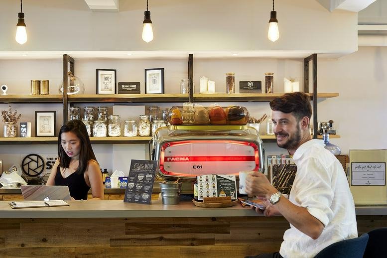 Communal cafe area at Cheung Hing Industrial Building featuring a wooden counter and espresso machine.