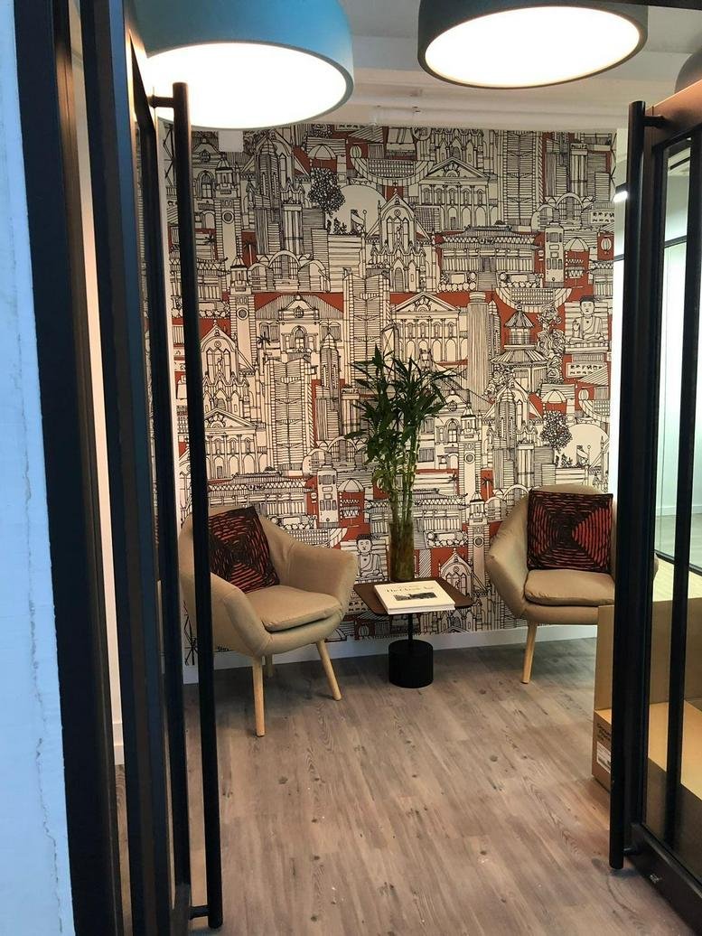 Modern lounge area at the Derrick Industrial Building featuring city-themed wallpaper and tan armchairs.