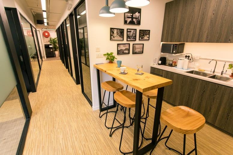 Modern office pantry and break area with high-top seating and a kitchen corner.