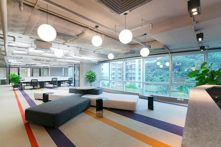 Spacious communal lounge at Eastern Central Plaza with globe pendant lights, colorful floor stripes, and large windows.