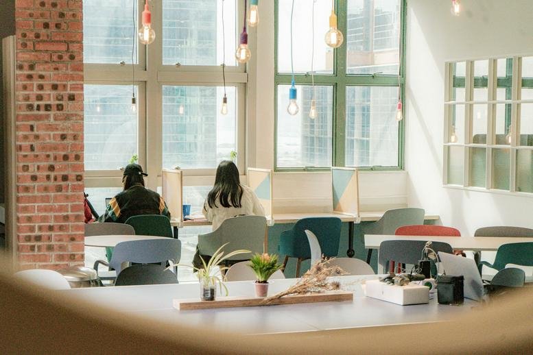 Bright coworking lounge at Entrepot Centre with colorful chairs, brick accents, and hanging light bulbs.