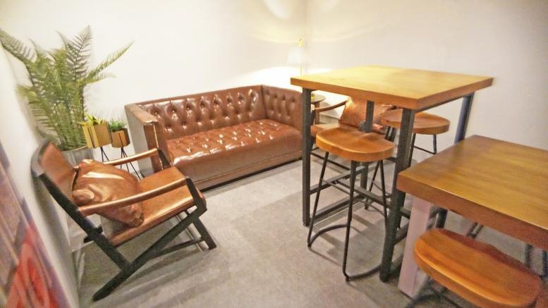 Communal breakout space at Eton Tower, 8 Hysan Avenue with leather sofa and high wooden tables.