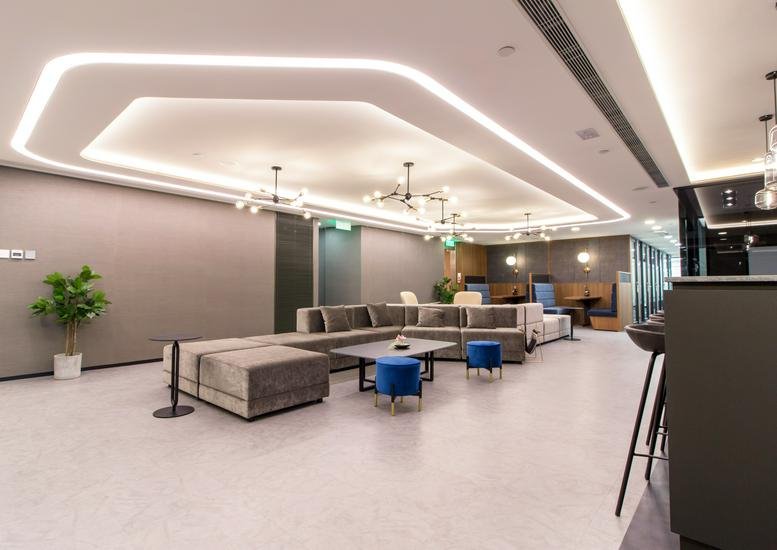 Spacious communal lounge at Infinitus Plaza with a modern geometric ceiling light and plush seating.