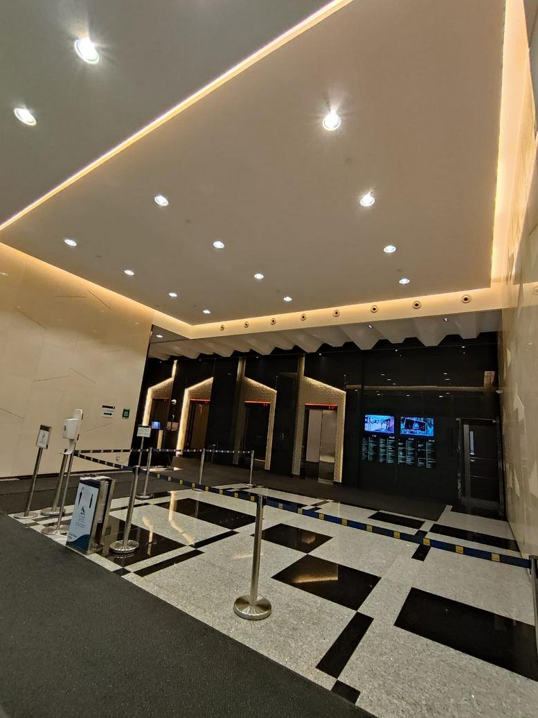Spacious building lobby featuring polished stone floors and a dark feature wall with elevator banks.