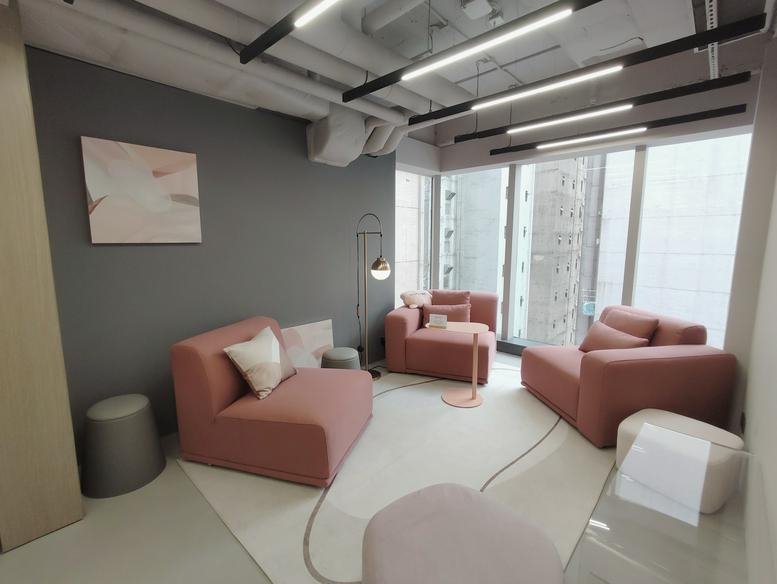 Chic lounge area with pink modular sofas, gray ottomans, and modern track lighting.
