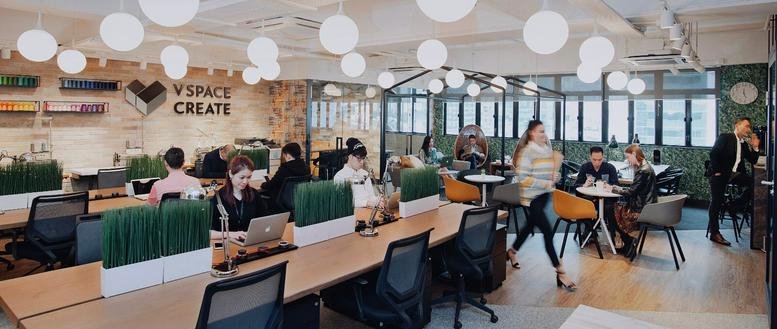 Vibrant coworking area at Riley House, 88 Lei Muk Road with warm lighting, plants, and various seating options.