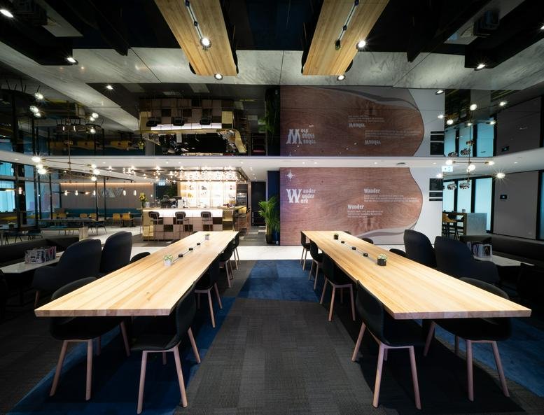 Spacious coworking area at The Gateway Tower 5 with long wooden communal tables and a bar in the background.