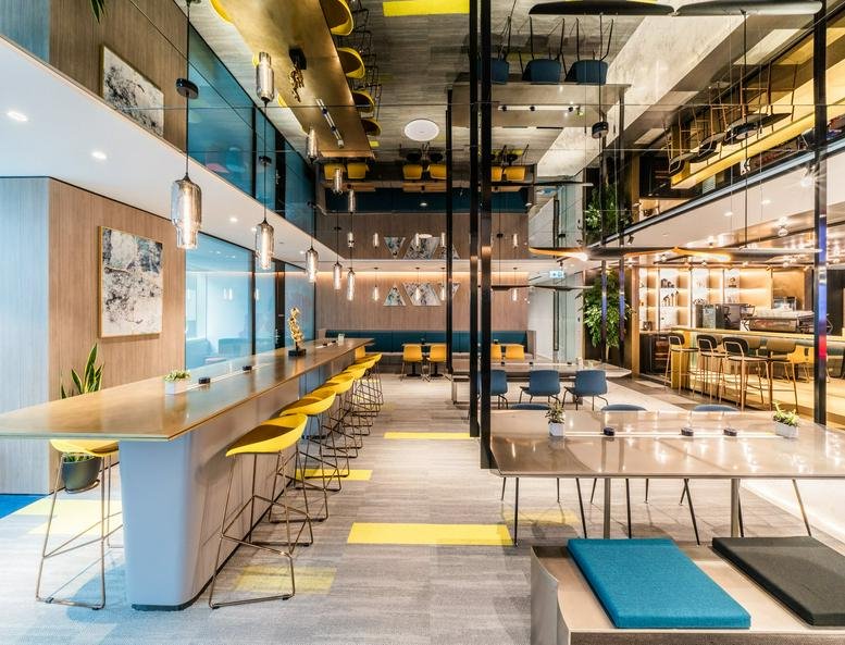 Spacious communal lounge at The Gateway Tower 5 with long tables and bright yellow stools.