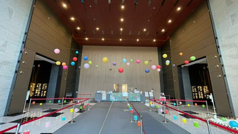 High-ceilinged building lobby decorated with colorful hanging paper lanterns.