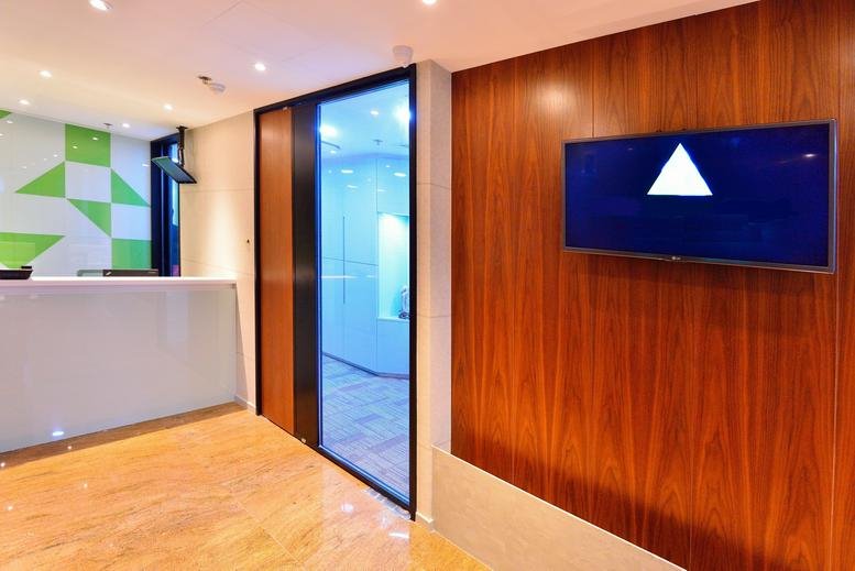 Reception area of Woon Lee Commercial Building with wood paneling and a branded screen.