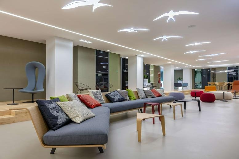 Spacious communal lounge at Wui Wah Factory Building with grey sofas and bird-shaped ceiling lights.