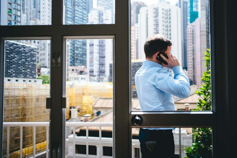 A man on a phone call looking out of a window at the Yu Yuet Lai Building.