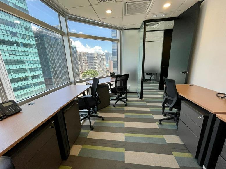Bright office space with corner windows offering expansive city views and multiple workstations.