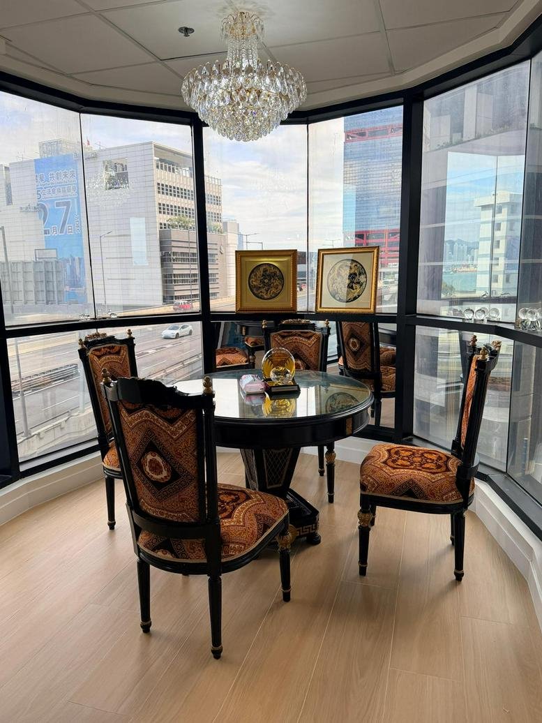 Communal dining area at 1 Des Voeux Road West with ornate chairs, a chandelier, and panoramic city views.