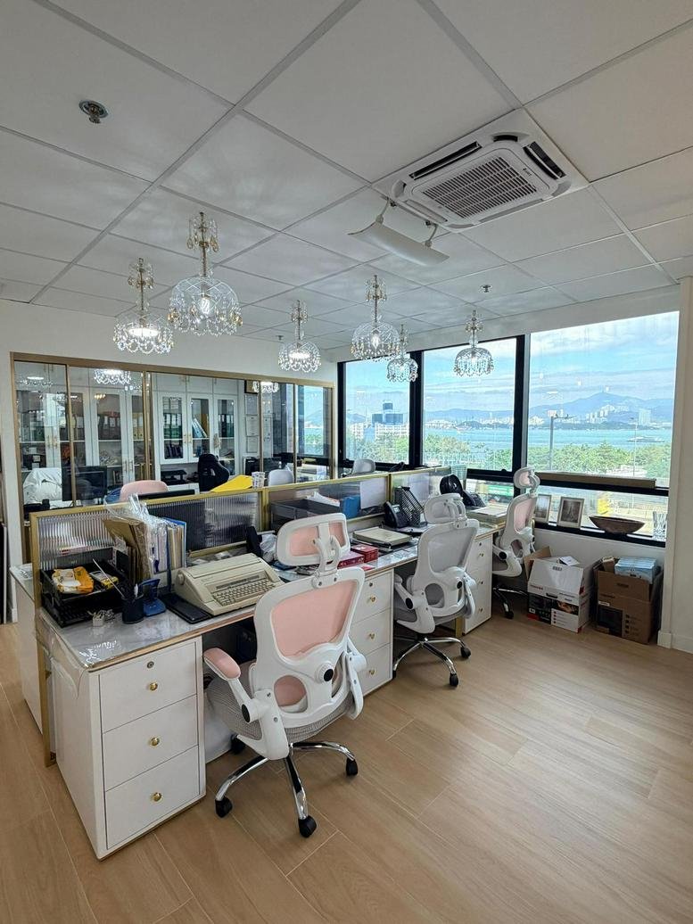 Spacious communal workspace with hardwood floors, multiple desks, and decorative globe pendant lighting.