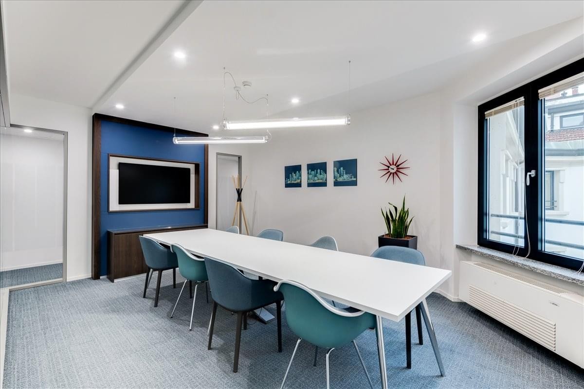 Meeting room at Centre Parc with a long white table, teal chairs, and a blue feature wall.